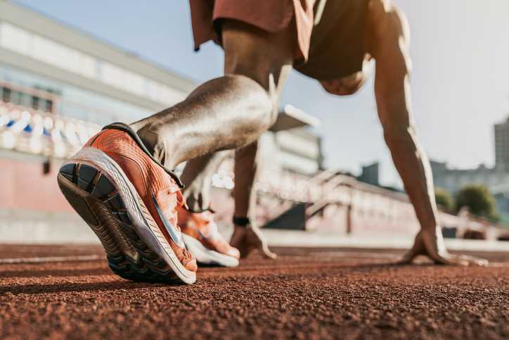 atlanta ankle and foot, man crouched on a track starting line, with ankle and orange Nike-clad foot in the foreground