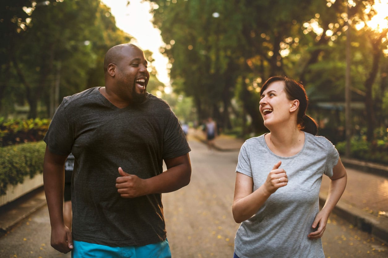 sciatica treatment specialist, image of a man and a woman happily jogging side by side in the park.