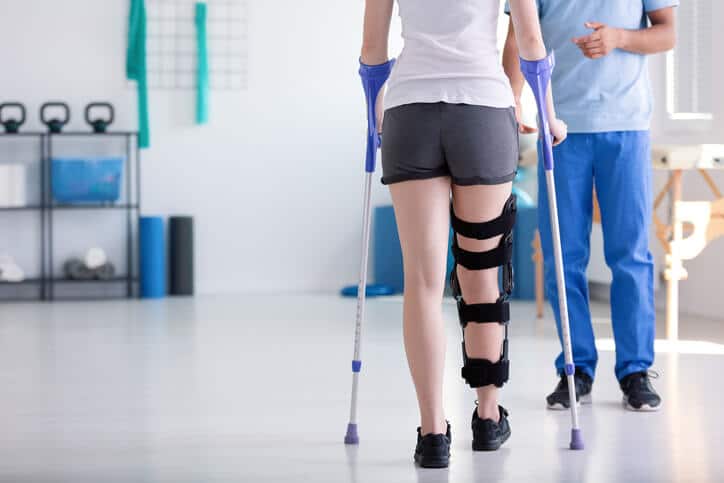 atlanta orthopedics, Physical therapist helping woman with right leg injury and crutches walk