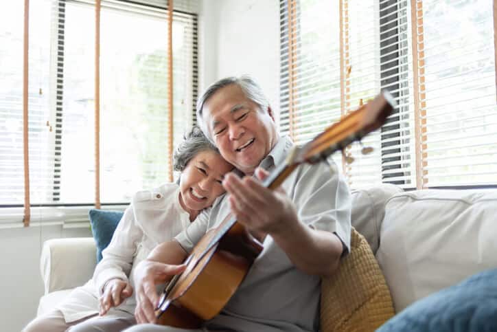 wrist pain treatment, image of happy elderly couple sitting on the couch while the man plays the guitar.