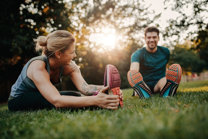 Prolotherapy, A man and woman couple wearing athletic clothing and sneakers stretch their legs on the grass in the park