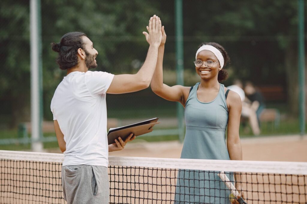 elbow and upper arm pain Male tennis instructor giving a high five to female student
