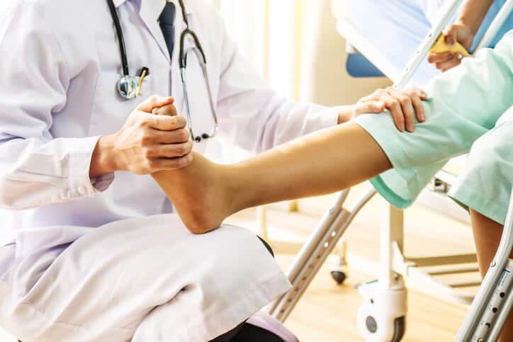 Auto Injury Treatment, Doctor lifting patient's left foot and examining their leg