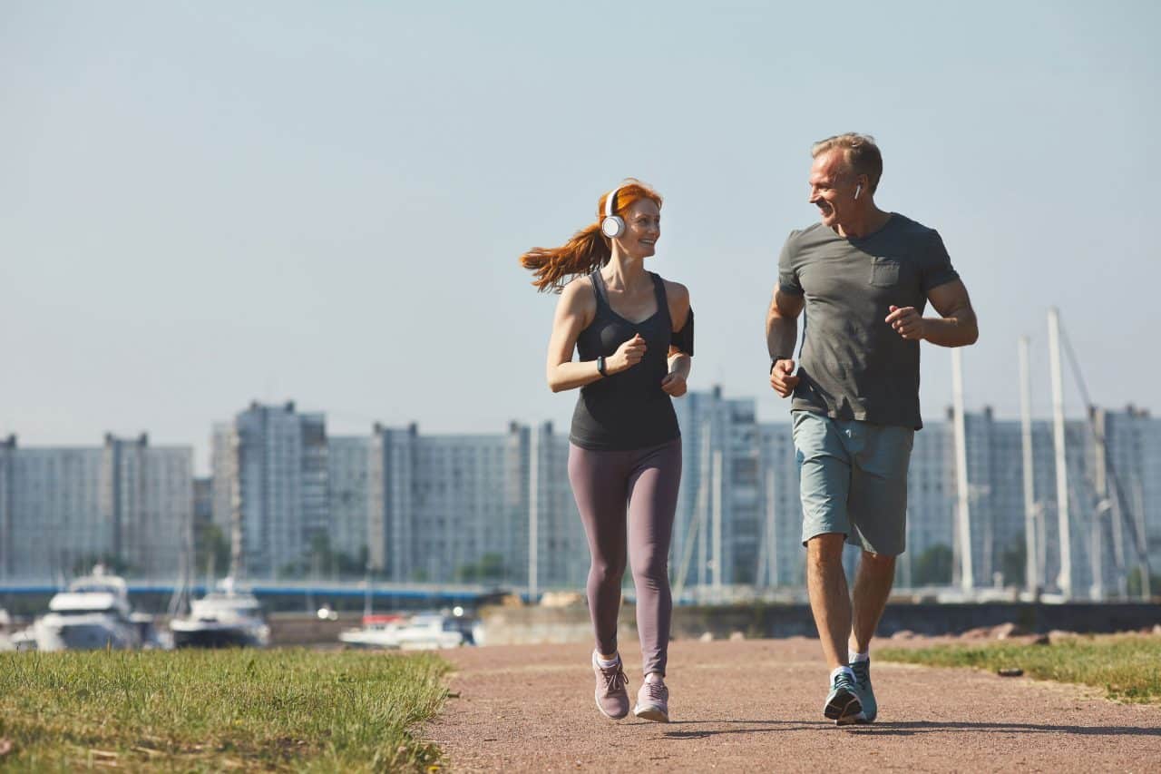 Stem Cell Therapy, Man and woman couple wearing athletic clothing jobs together side-by-side on a park path with a boat marina in the background
