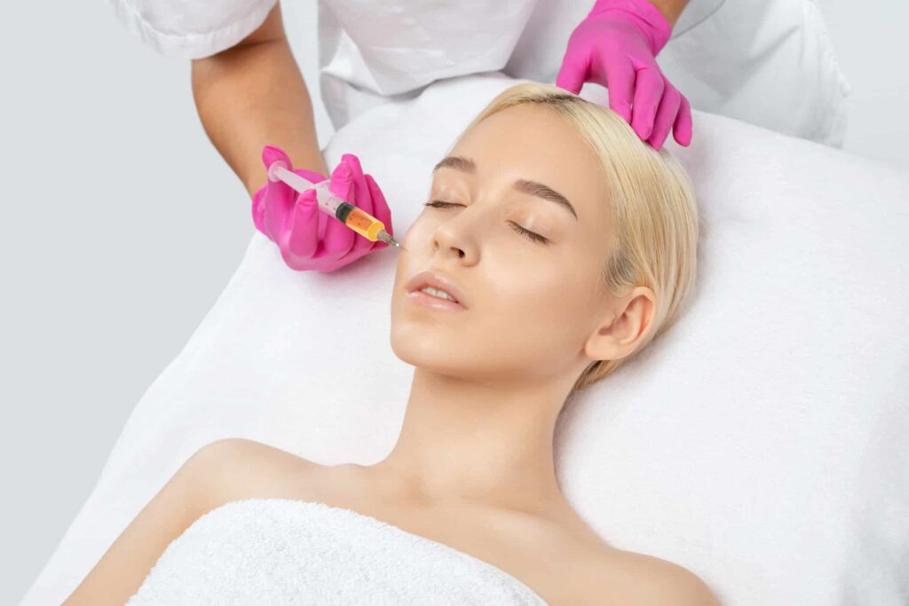 Vampire Facial® & Facelift​, image of a young woman receiving a face injection in her right cheek.