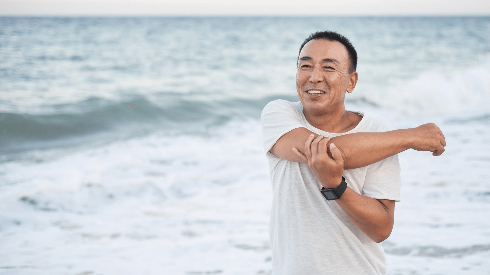 Vitamin C IV Therapy; image of a happy man stretching his right shoulder and arm on the beach.
