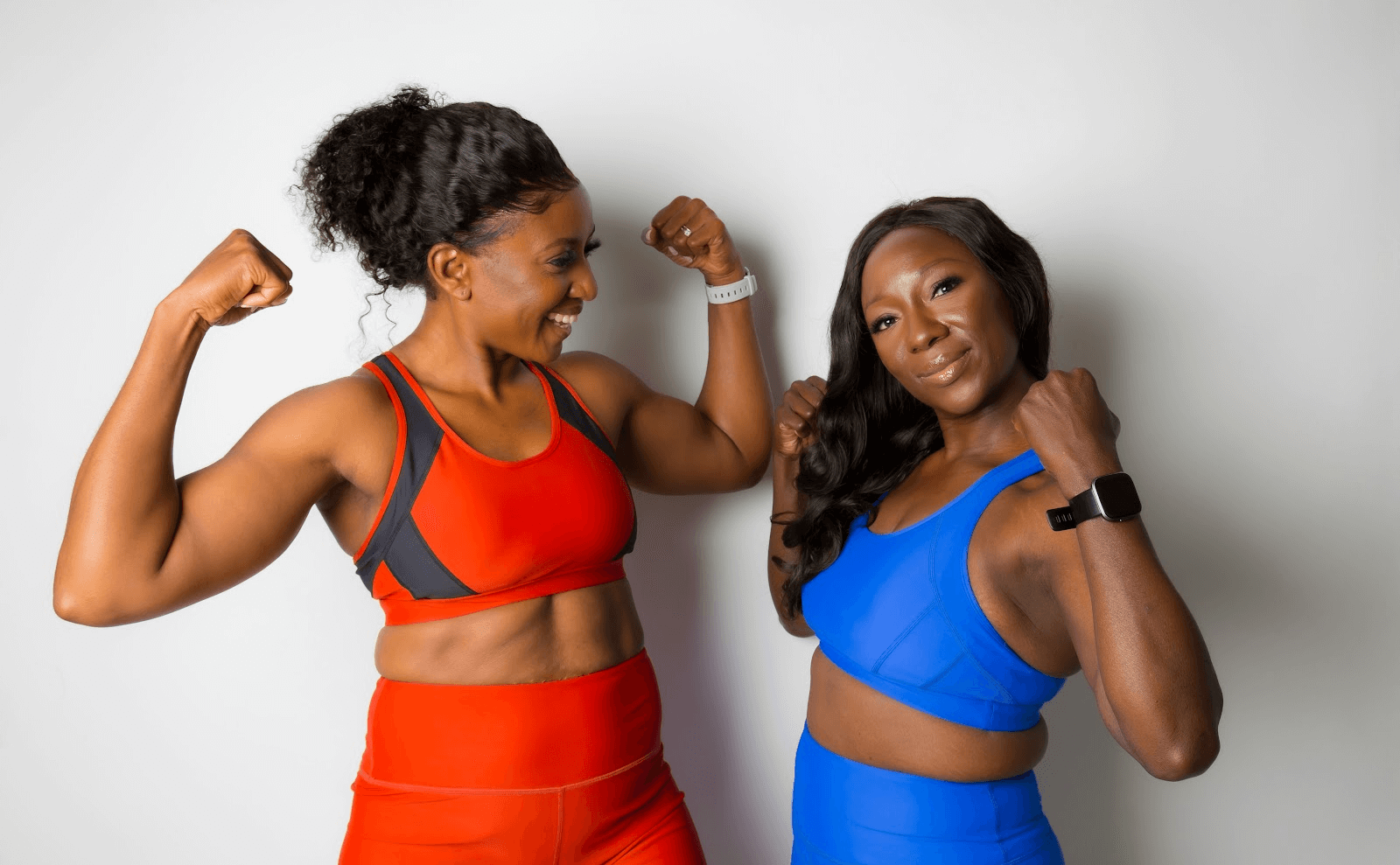Vitamin C IV Therapy; image of two happy women wearing workout gear flex their arm muscles.