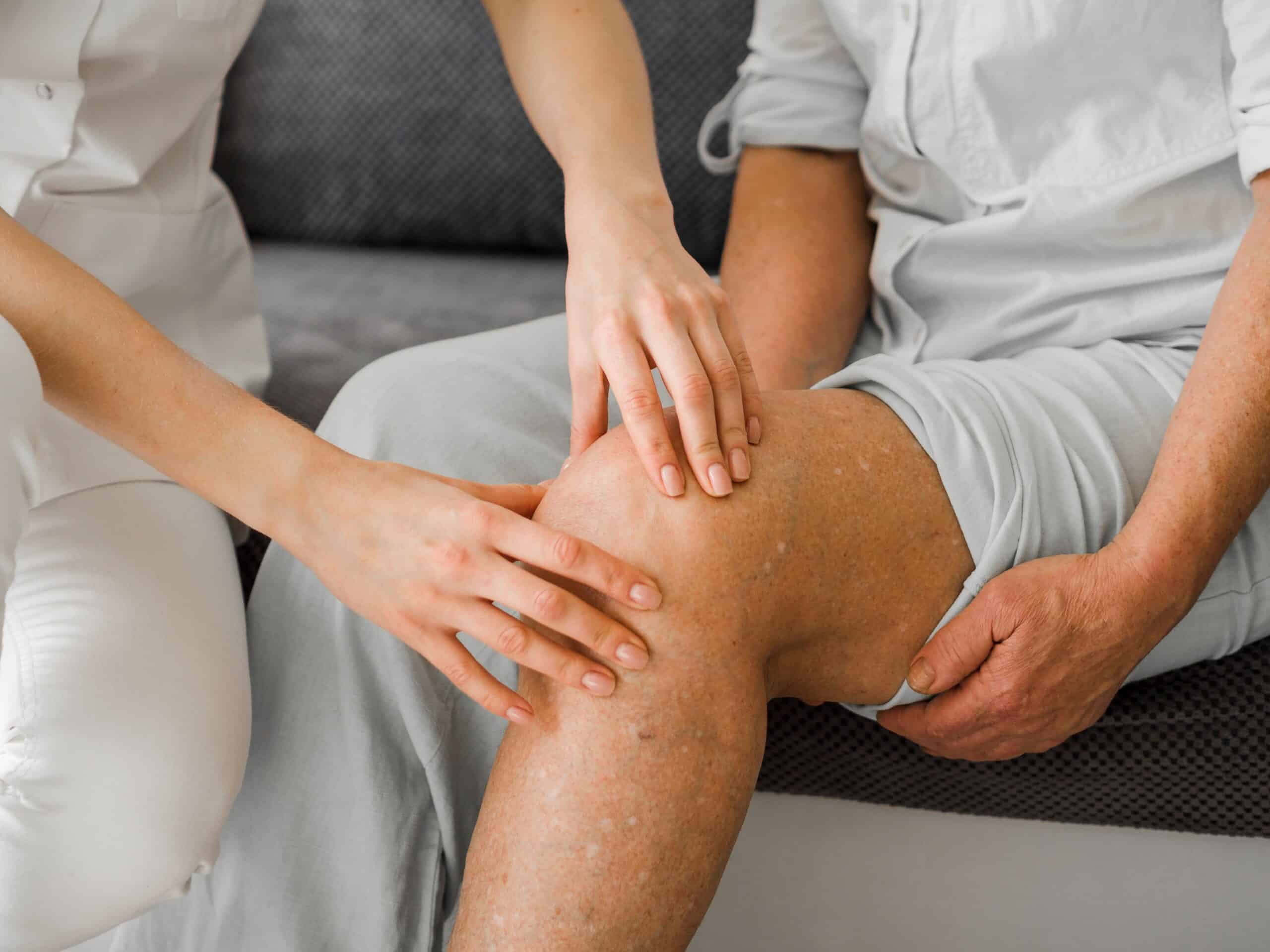 PRP injection for knee; image of a woman practitioner placing both hands on an elderly man’s left knee.