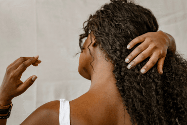 Image of a woman pulling her long dark hair to her right side.