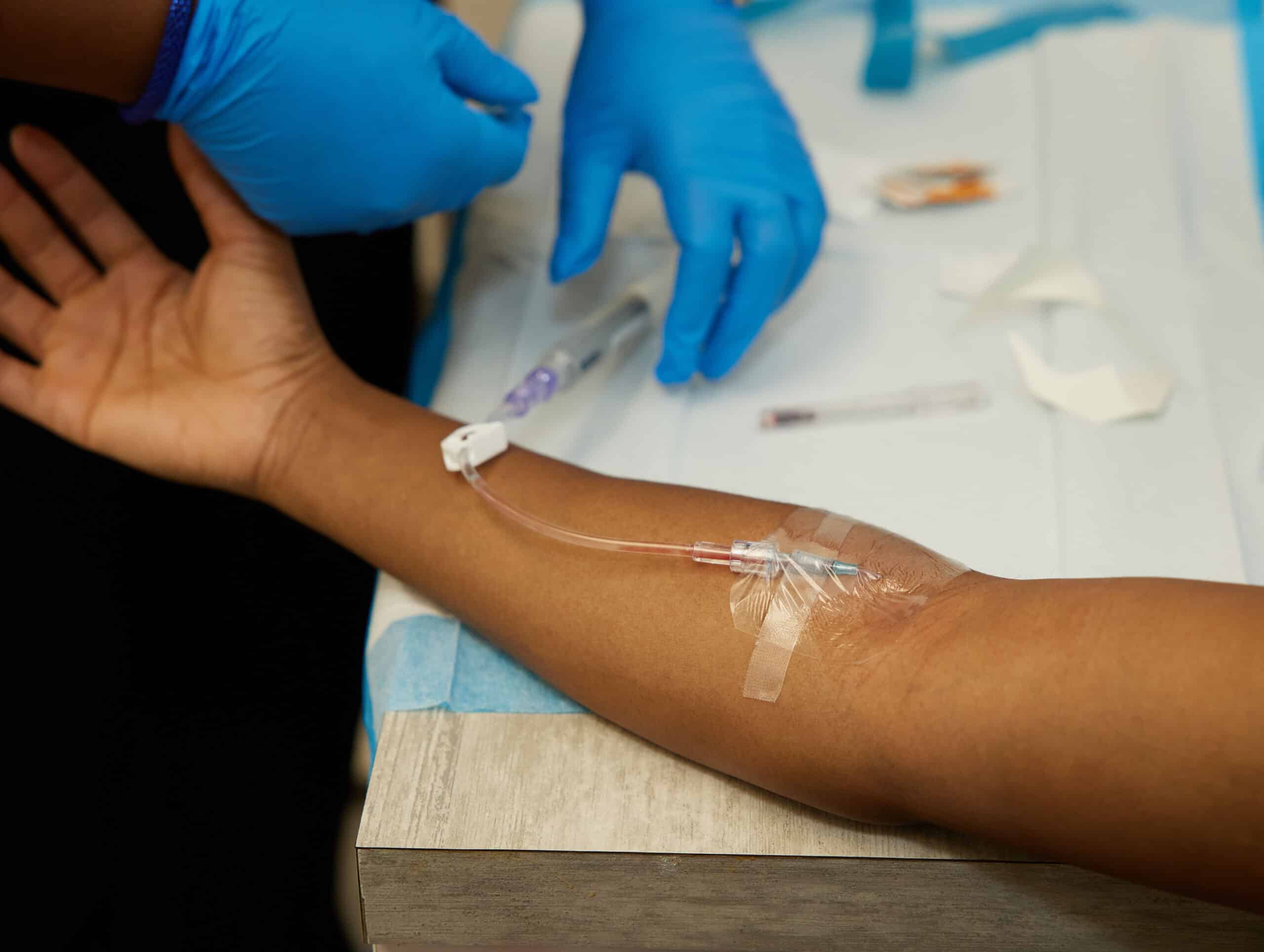 ozone therapy atlanta, Image of a nurse inspecting an IV that is inserted into a female patient’s forearm.