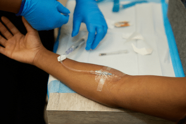 Image of a IV needle inserted into a female patient’s arm.