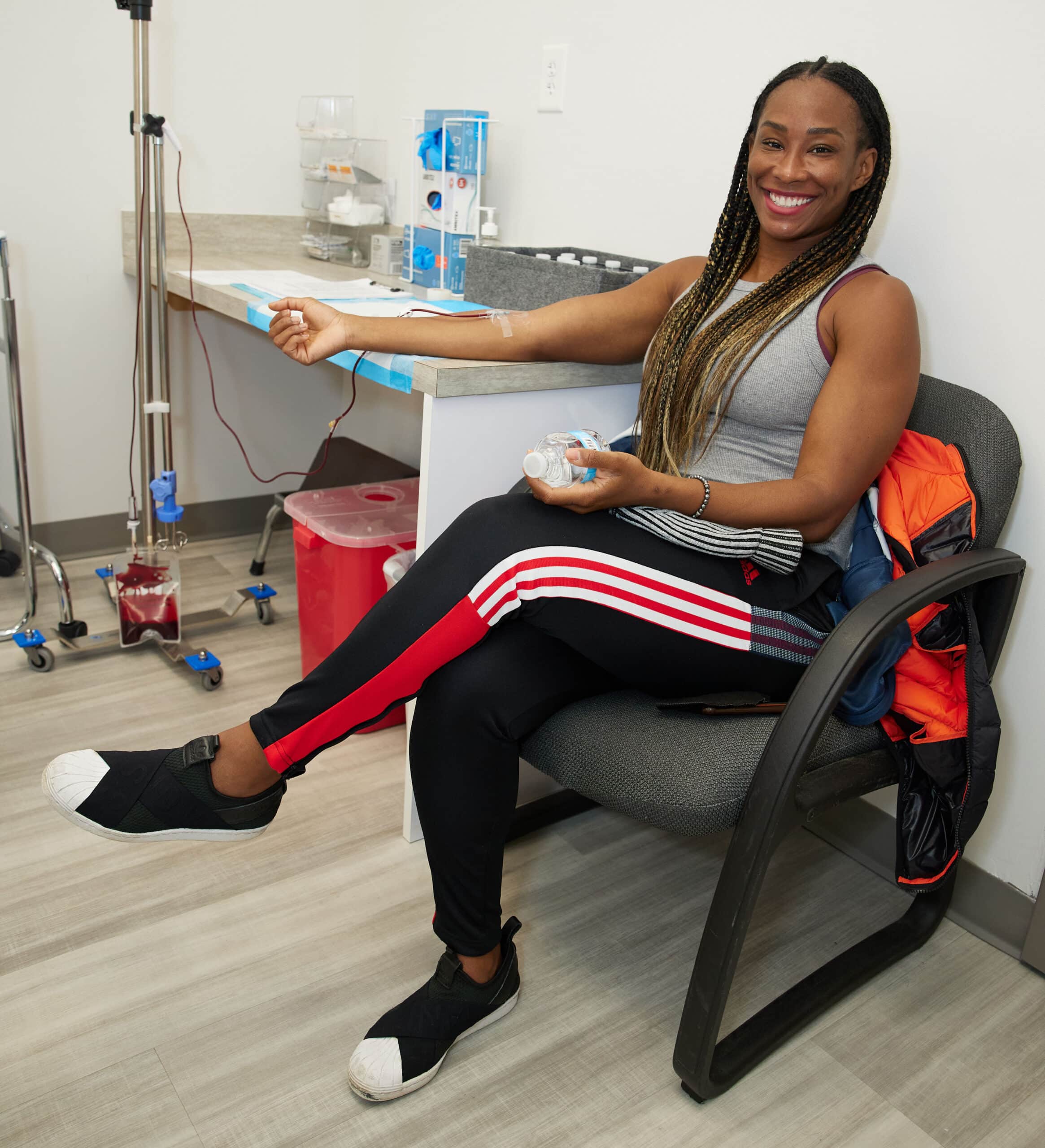 ozone therapy atlanta, Image of a smiling woman sitting in a chair in a patient’s room receiving Ozone IV Therapy treatment in her right arm.