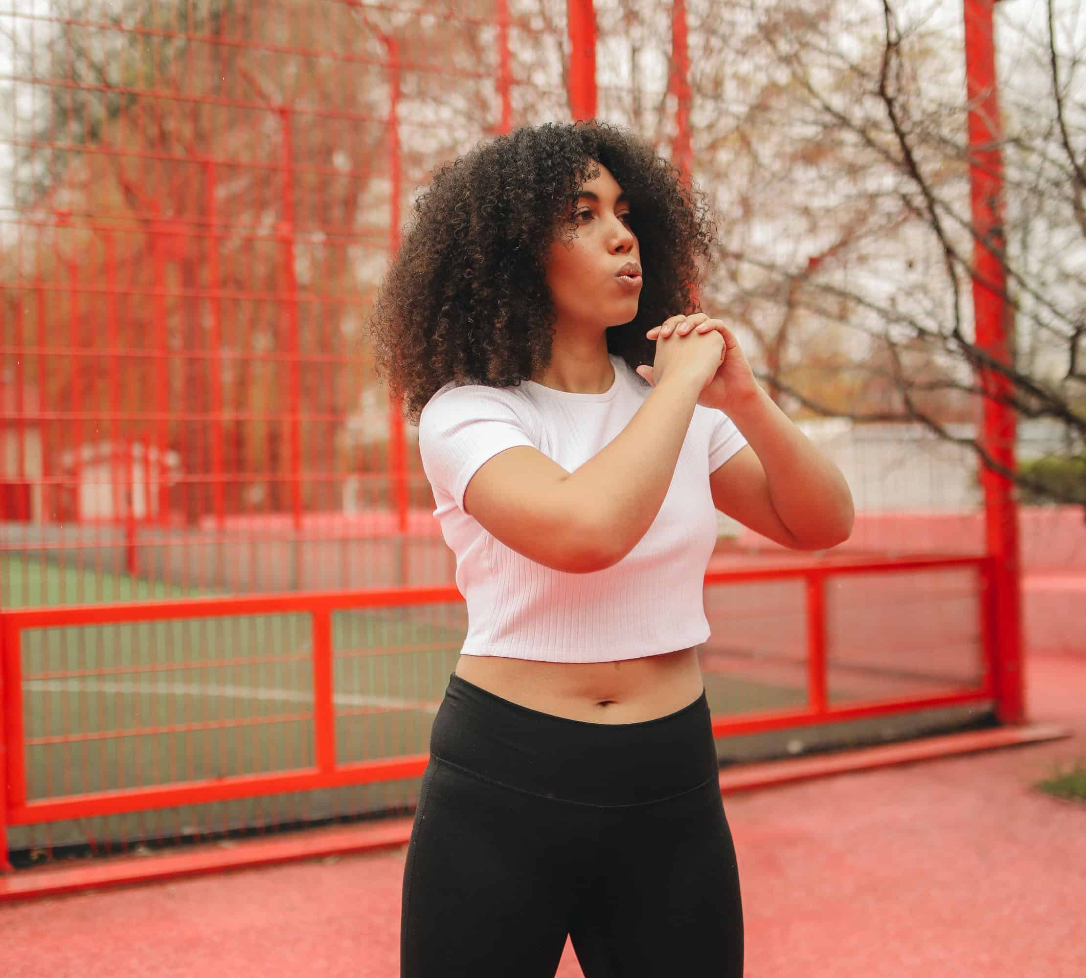 ozone therapy atlanta, Image of a woman wearing a white crop-top and black leggings working out in the park.