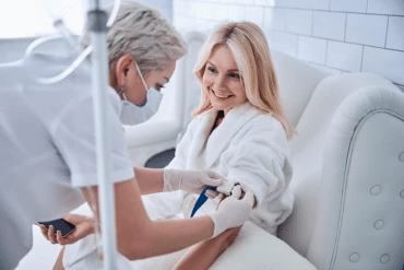 Image of a female doctor inserting an IV needle into a female patient’s left arm.