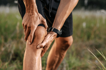 Image of a man grasping his right knee with both of his hands.