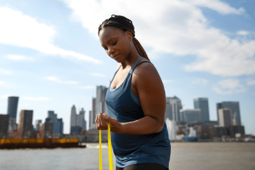 Image of a woman exercising with an arm band with the city in the background.