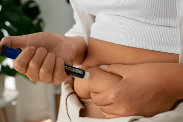 Image of a woman inserting an injection into her abdomen.