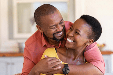 Image of a happy man embracing a smiling woman from behind.