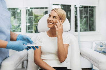 Image of a happy female patient sitting in a reclining chair, talking with the doctor.