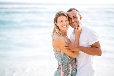 Image of a happy couple in embrace with the ocean in the background.