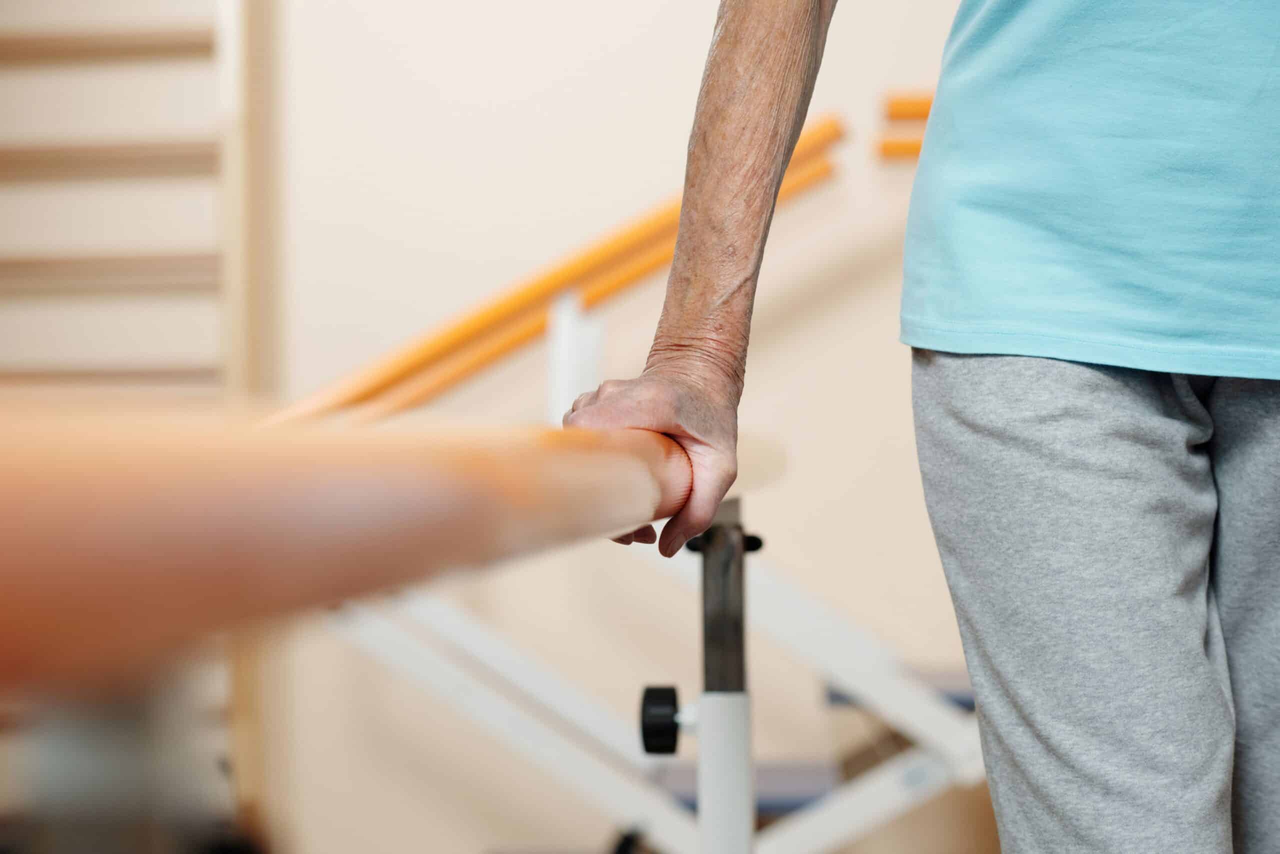 Gait training, image of an older man holding a balance beam to his right to balance while walking.